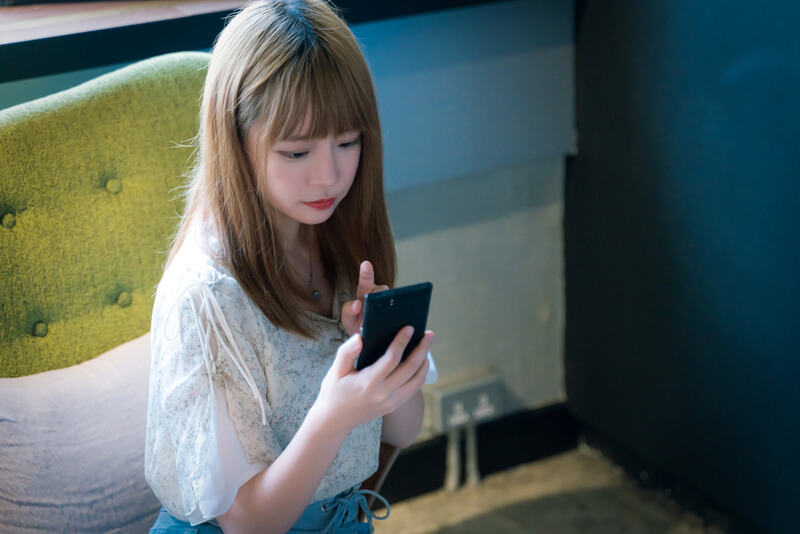 スマホを持つ金髪の女性